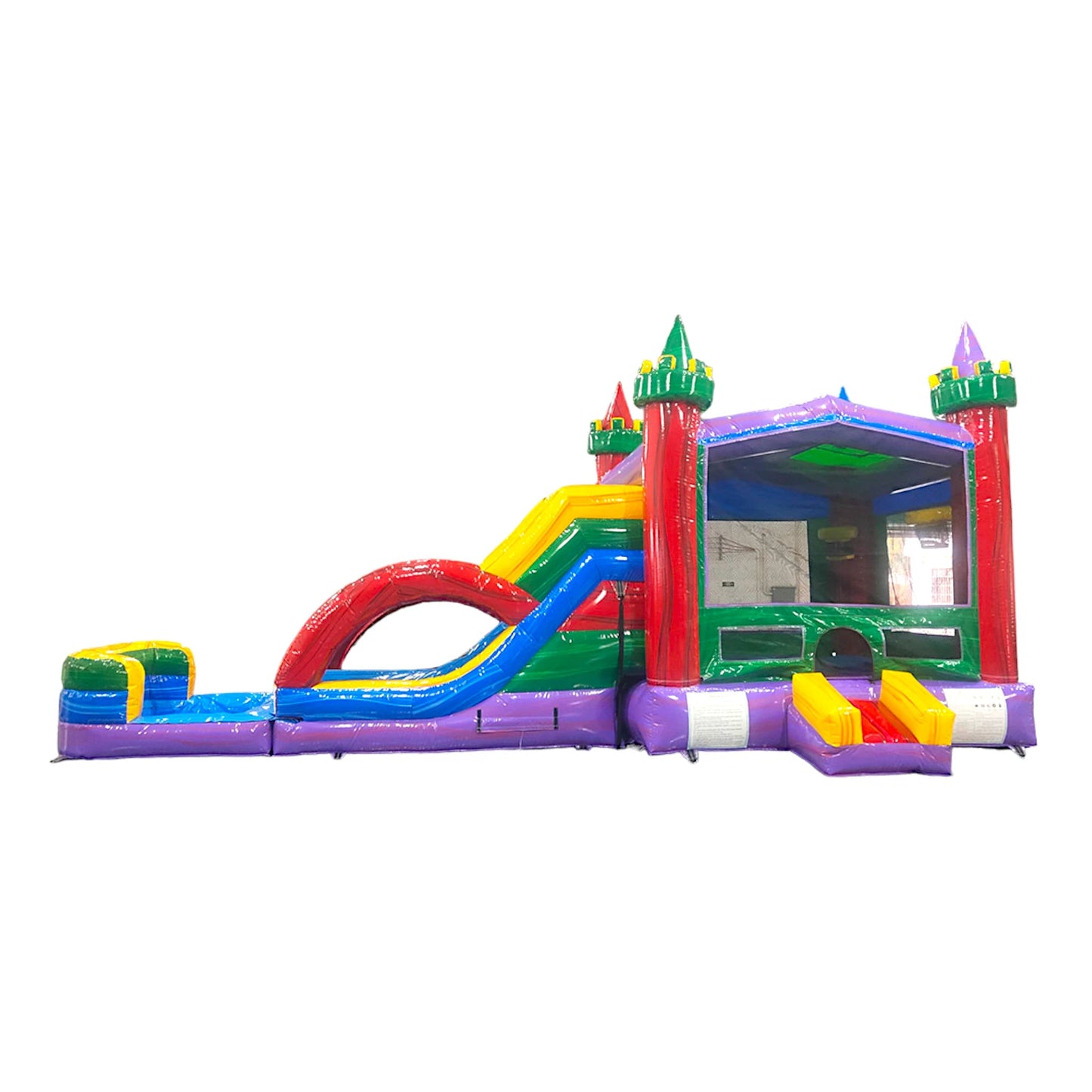 Large colorful inflatable castle-themed combo featuring dual curved slides in red and blue. The structure has vibrant purple, yellow, green, and red colors with castle turrets and flags. Includes a spacious bounce house area with mesh windows and a splash pool at the base. Set against a white background, showcasing its multi-functional wet/dry design.