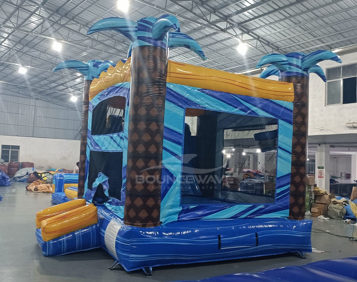 Flashpoint Dual Lane Commercial Inflatable Combo (Wet/Dry) displaying tropical-themed bounce house with palm trees, dual entrances, and attached blue and yellow water slide
