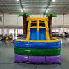 Front view of Goombay Splash Dual Lane Commercial Inflatable Combo set up in a large indoor warehouse. Features dual curved blue slides, inflatable palm trees, a yellow and blue bounce house area, and a splash pool. The "BOUNCEWAVE Inflatable Sales" logo is visible on the base. Metal roofing and other inflatable products visible in the background.