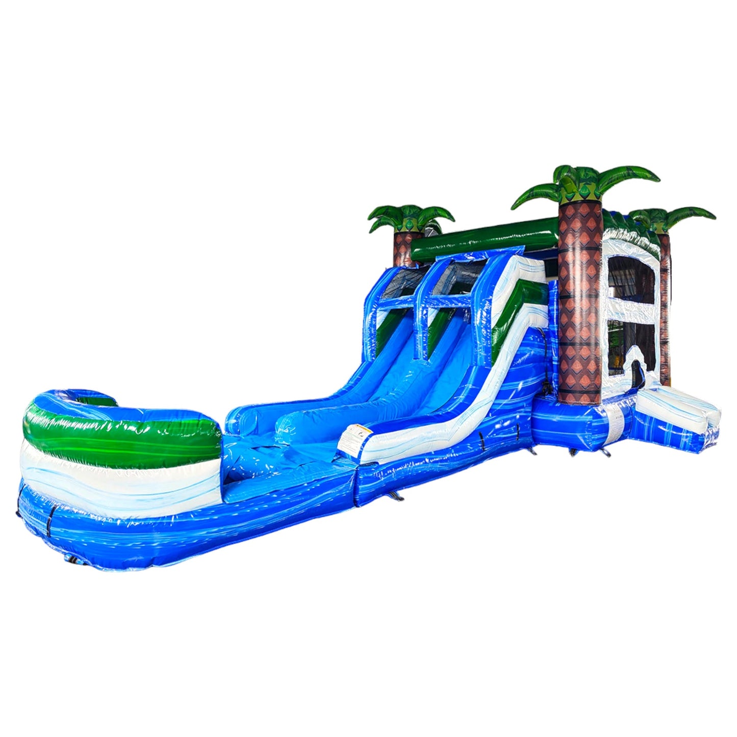 Wide-angle view of Island Thunder Dual Lane Commercial Inflatable Combo (Wet/Dry) isolated on a white background. The inflatable features dual blue water slides, palm tree pillars, a white bounce house structure, and a blue splash pool base. The tropical theme is highlighted by the green palm leaves and brown tree trunks.