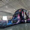 Wide-angle view of MoonWalker Commercial Econo Inflatable Wet/Dry Combo featuring a space-themed bounce house with cosmic design, attached slide, and play area. The inflatable has bright purple, blue, and pink colors with astronaut and rocket decorations. Set up in an indoor warehouse with metal roofing and other inflatable products visible.