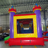 Rear view of Multi Color Castle Commercial Econo Inflatable Combo (Wet/Dry) showing the bounce house entrance with purple turrets and yellow frame. Interior visible through mesh windows. Set up in an indoor warehouse with other inflatable products and equipment in the background.