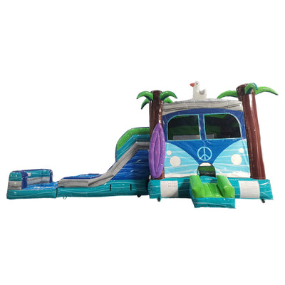 Side view of Retro Splash Dual Lane Commercial Inflatable Combo isolated on a white background. The inflatable showcases a blue and pink retro van design with a peace sign, dual blue slides, inflatable palm trees, a surfboard, and a splash pool area. The design highlights its vintage beach theme for commercial wet/dry use.