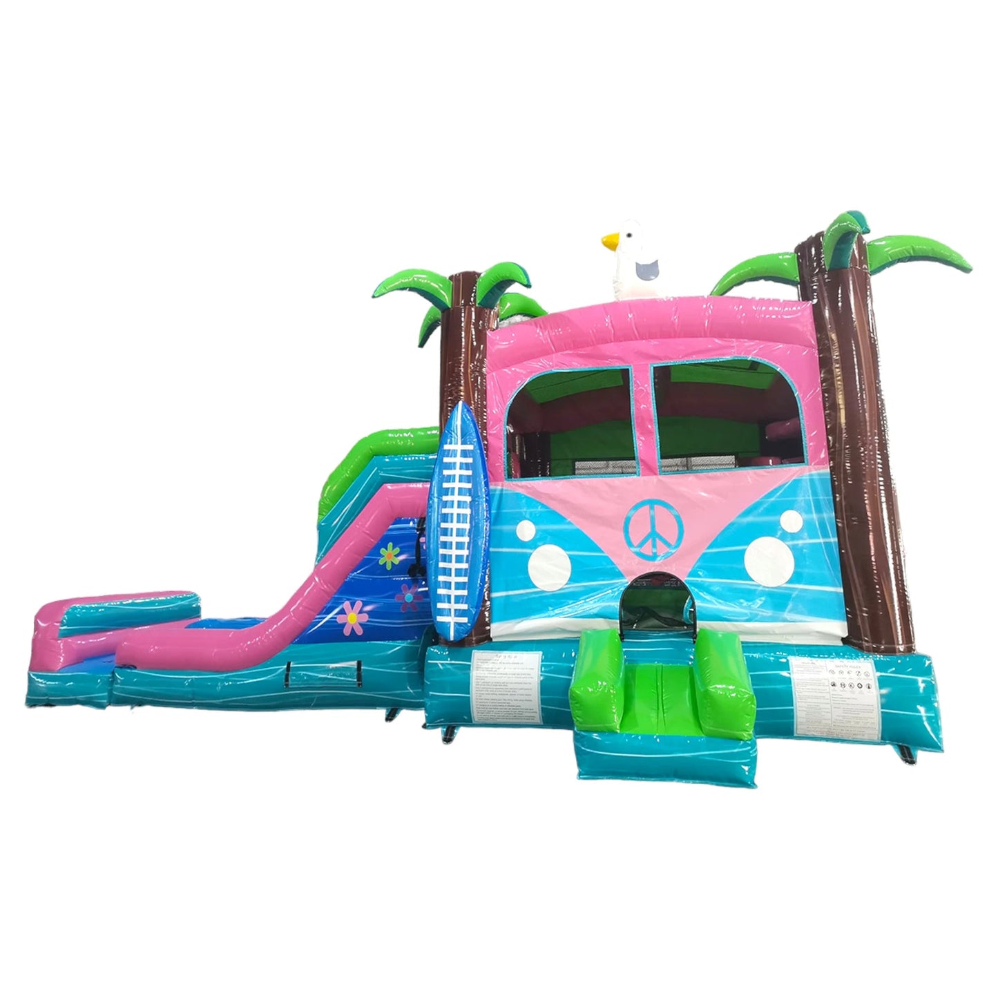 side view of Retro Splash Dual Lane Commercial Inflatable Combo featuring a vintage van design. The structure has dual blue slides, a pink and blue van-shaped bounce house area with a peace sign, inflatable palm trees, and a surfboard. Set against a white background, showcasing its retro beach theme for commercial wet/dry use.