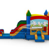 Side view of Seasonal Sampler Commercial Econo Inflatable Panel Combo featuring a colorful castle-like structure with multiple towers and spires. The inflatable has dual slides, one red and one blue, emerging from a yellow and red base. A bounce house area with mesh windows is visible. The panel displays a cheerful scene with cartoon rabbits in a meadow.
