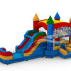 Front view of Seasonal Sampler Commercial Econo Inflatable Panel Combo featuring a "Happy Birthday" themed panel with colorful balloons and festive text. The inflatable structure has castle-like towers in red, blue, and yellow, dual slides in red and blue, and a bounce house area with mesh windows. Set on a blue base with yellow entrance steps.
