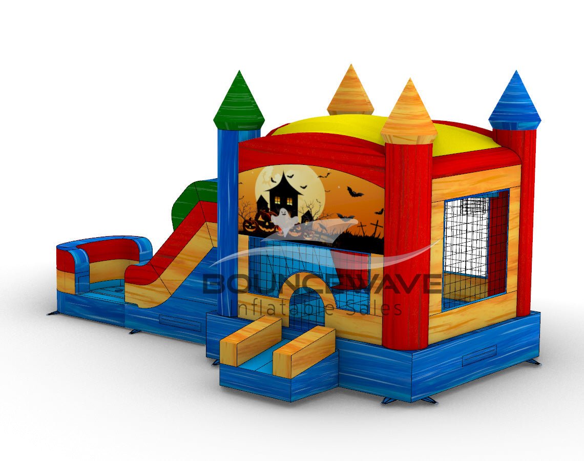 back view of Seasonal Sampler Commercial Econo Inflatable Panel Combo showcasing a Halloween-themed panel with a haunted house, ghost, and jack-o'-lanterns against an orange sky. The inflatable structure features colorful towers, dual slides in red and blue, and a bounce house area with mesh windows. Set on a blue base with yellow steps leading to the entrance.
