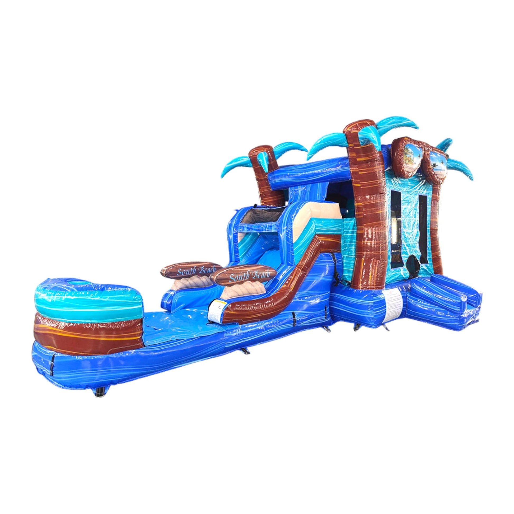 Side view of South Beach Econo Combo showing bright blue and turquoise design with inflatable palm trees, curved slide, and large splash pool area. The combo includes a bounce house with "South Beach" branding and is displayed against a white background.