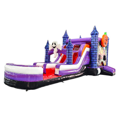 Full view of Spooky Splash Halloween Dual Lane Commercial Inflatable Combo isolated on a white background. The structure showcases blue castle towers, dual slides in red and purple, a large inflatable ghost figure, and an orange jack-o'-lantern on top. A colorful Halloween scene decorates the front panel, and a white and purple splash pool area is visible at the base.