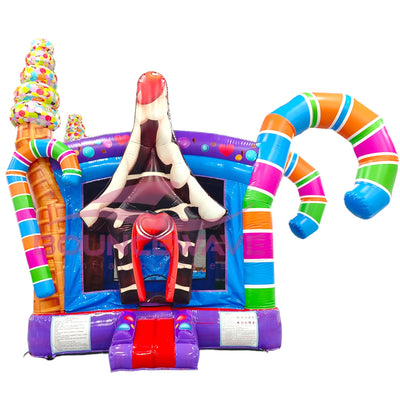 Colorful inflatable Sugar Rush Commercial Grade Bounce House featuring a candy-themed design. The structure has a large ice cream cone on the left, a curved candy cane on the right, and a central bounce area with blue walls and mesh windows. The entrance has a small slide and is decorated with candy-like patterns. The bounce house roof is adorned with multicolored sprinkles. Set against a white background.