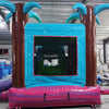 Front view of Summer Luau Econo Combo, showcasing the bounce house entrance flanked by inflatable palm trees, with a blue frame and colorful base. Set up in an indoor warehouse with other inflatable products and equipment visible in the background.