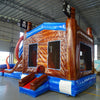 Rear view of Tentacle Typhoon Dual Lane Commercial Inflatable Combo set up in a warehouse. The inflatable displays a brown ship-like structure with blue trim, red octopus tentacles, and a bounce house area with mesh windows. Pirate flags are visible on top. Various other inflatable products and warehouse equipment can be seen in the background, demonstrating its commercial setting.