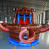 Close-up front view of Tentacle Typhoon Dual Lane Commercial Inflatable Combo showing the entrance area. Features a brown ship-like structure with blue trim, red octopus tentacles, and dual slides in red and blue. A large inflatable octopus head is visible at the top. Set in a warehouse with concrete flooring and various other inflatable products visible in the background.