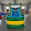 Front view of Tiki Wave Commercial Econo Inflatable Combo (Wet/Dry) featuring a vibrant tropical-themed design. The inflatable structure includes a large blue curved slide with white foam crest, yellow bounce house with green tiki face pillars, and a green base with yellow stripe. An inflatable cloud and palm tree top the structure. The combo is set up in an indoor warehouse, with other inflatables and equipment visible in the background, showcasing its commercial use and wet/dry functionality.