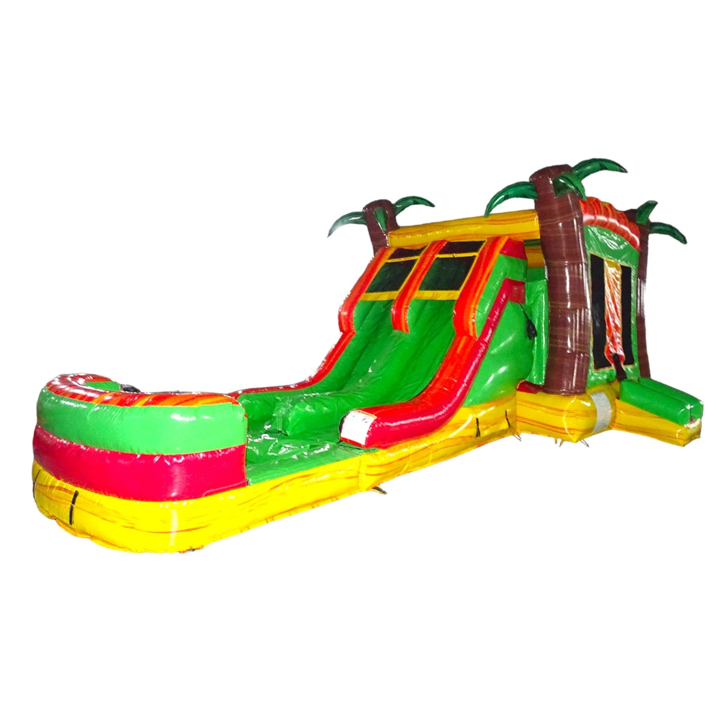 Side view of Tropical Inferno Dual Lane Commercial Inflatable Combo isolated on a white background. The inflatable displays dual red slides, brown palm tree trunks with green leaves, and a colorful base with green, red, and yellow sections. A large splash pool area is visible at one end, highlighting its design for commercial wet/dry use.